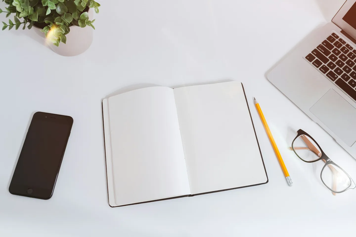 A bright desk with a laptop, open notebook and phone