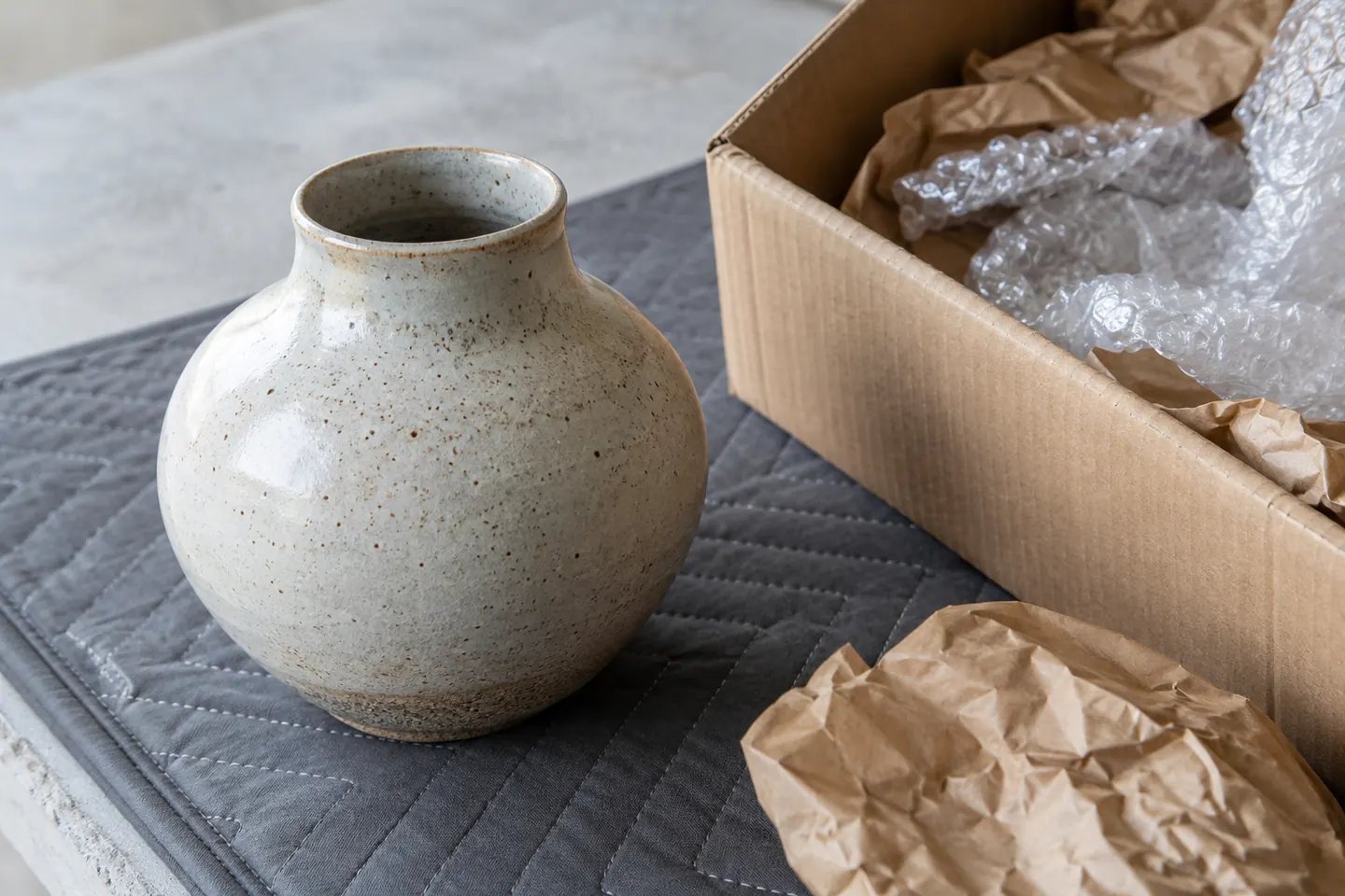 Close-up of a returned ceramic object on a padded inspection mat beside its packaging